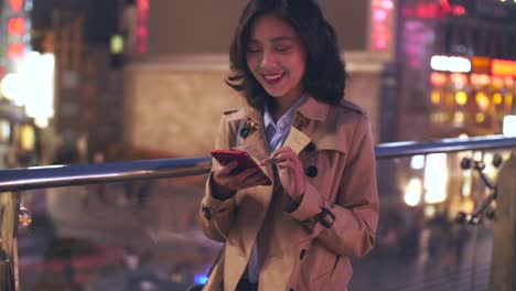 slow-motion--of-pretty-happy-young-asian-woman-using-mobile-phone-in-the-city-at-night