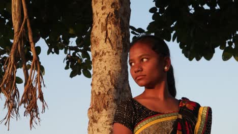 Adolescente-India-hermosa-chica-viendo-en-una-cima-de-la-colina-debajo-de-un-árbol-en-un-día-de-verano-de-amor-impaciente-alegría-feliz-sol-tropical-caliente-brillante-sol-contenido-mirando-a-cámara-handheld-estabilizado