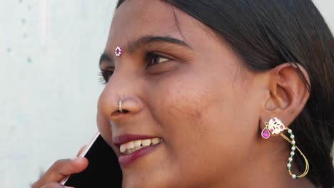 Young-lady-with-beautiful-face-on-mobile-phone-cellphone-handy-smart-contact-notification-types-message-talks-speaks-communication-device-wireless-network-signal-smile-laughs-close-up-in-Rajasthan