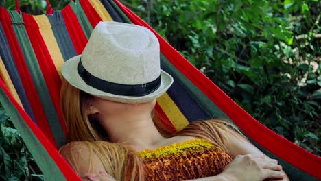 Mujer-joven-durmiendo-en-hamaca-con-sombrero-que-cubre-la-cara