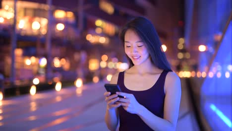 Beautiful-Asian-Woman-Outdoors-At-Night-Using-Mobile-Phone