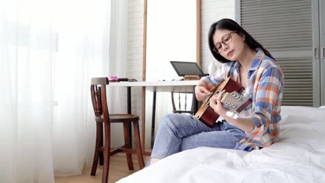 Frau-spielt-Gitarre-in-ihrem-Bett