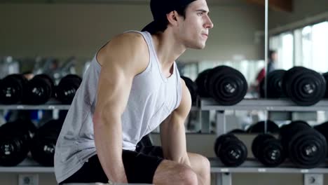 Un-chico-sin-camiseta-en-el-gimnasio,-entrena-su-cuerpo-para-mantenerse-en-forma-y-han-definido-los-músculos.-El-atleta-provoca-fatiga-y-cargas-pesadas.