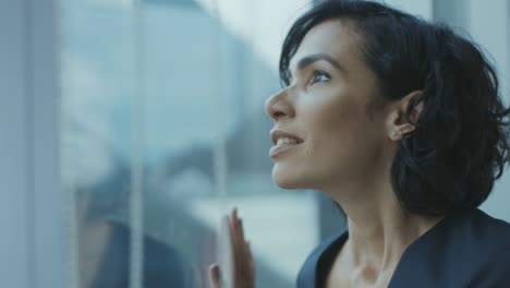 Close-up-Portrait-of-the-Beautiful-Young-Businesswoman-Looking-Thoughtfully-out-of-Her-Office-Window.-Confident-and-Attractive-Hispanic-Woman-Thinking-about-Her-Business-Project.