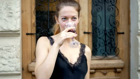 Young-woman-drinks-wine-from-a-crystal-glass-and-enjoys-a-drink.-Leisure-of-successful-people-on-the-road.