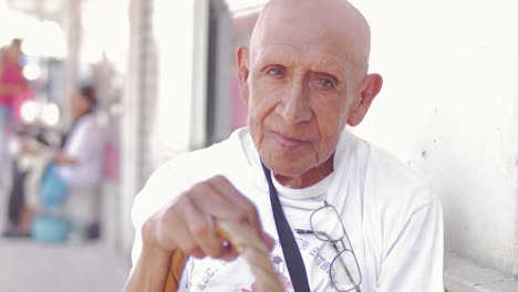 An-old-bald-hispanic-man-holding-a-basket-on-a-sidewalk-in-Mexico