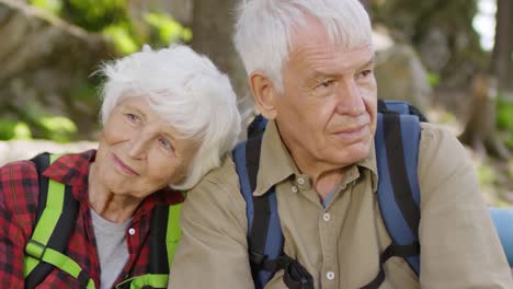 Tender-Senior-Couple-Resting-in-Forest-during-Hike