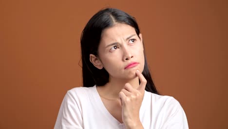 Denken-Frau-isoliert.-Porträt-von-Asiatin-im-weißen-T-shirt-denken-schwer-und-aufgeregt,-um-eine-Lösung-zu-finden,-Blick-in-die-Kamera.