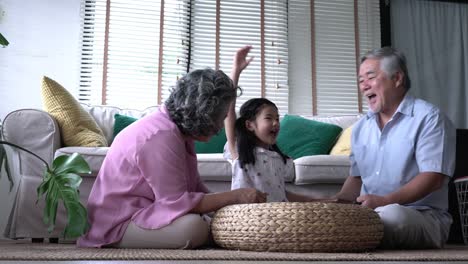 Couple-senior-and-kids-girl-playing-puzzle-games-together-in-living-room-at-home.-Concept-of-caucasian-family,-education,-growing-learn-and-development-of-age.-4k-resolution.