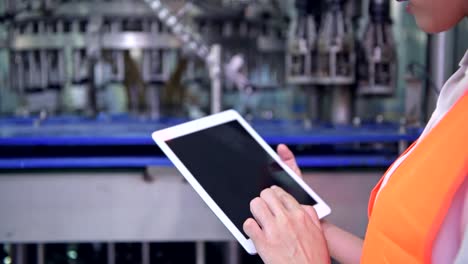 Mujer-ingeniero-industrial-en-el-trabajo-en-la-fábrica.-Hermosa-joven-ingeniero-chino-trabajando-en-fábrica-grande.-Con-casco-y-chaqueta.-Máquina-automática-de-alta-tecnología-en-segundo-plano.