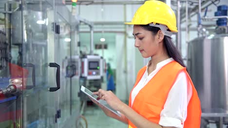 Mujer-ingeniero-industrial-en-el-trabajo-en-la-fábrica.-Hermosa-joven-ingeniero-chino-trabajando-en-fábrica-grande.-Con-casco-y-chaqueta.-Máquina-automática-de-alta-tecnología-en-segundo-plano.