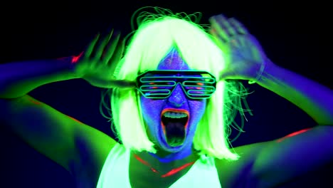 Woman-with-UV-face-paint,-wig,-glowing-glasses,-clothing-portrait-acting-crazy.-Caucasian-woman.-.