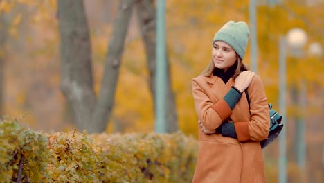 Hermosa-joven-morena-caminando-en-el-parque-en-otoño