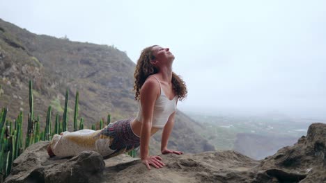 Young-Caucasian-woman-performing-upward-facing-dog-pose-outdoors.