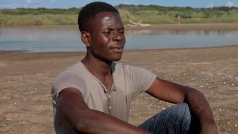 Pensive-upset-black-african-man-alone-on-the-beach--missing,family,home