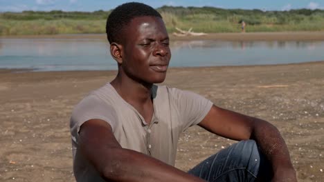 Nachdenklich-verärgert-schwarzen-afrikanischen-Mann-allein-auf-dem-Strand---fehlt,-Familie,-Haus