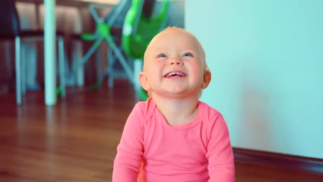 Smiling-cute-little-girl-sitting-on-floor-of-house-in-room
