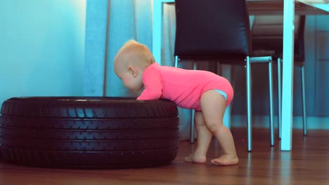 Cute-little-child-touches-and-looks-at-the-car-wheel.-Kid-is-studying-the-car-wheel