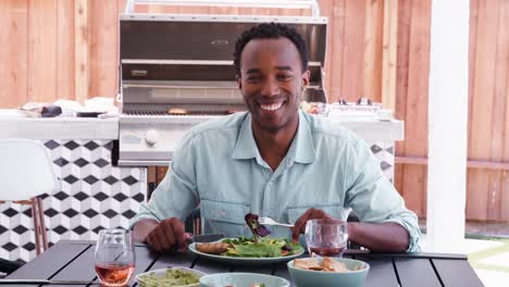 Joven-negro-almuerzo-hombre-comiendo-en-una-mesa-en-el-jardín