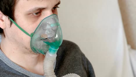 Verwenden-Sie-Vernebler-und-Inhalator-für-die-Behandlung.-Das-Gesicht-des-Mannes-Closeup-durch-Inhalator-Maske-einatmen.-Ansicht-von-vorne.