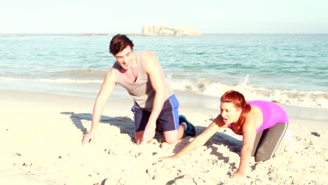 Smiling-couple-doing-push-ups-at-the-beach