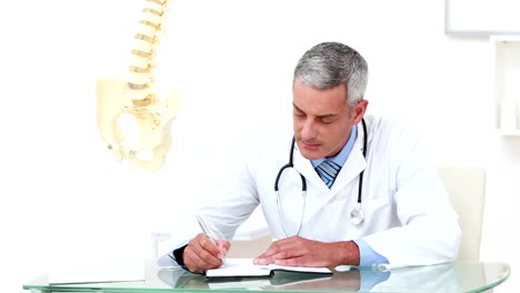 Doctor-working-at-his-desk-and-smiling-at-camera