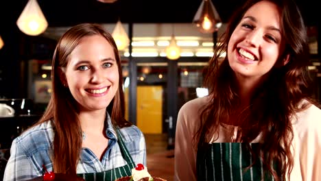 Smiling-waitresses-showing-cakes