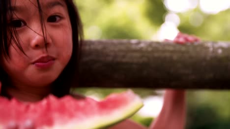 Wenig-asiatische-Mädchen-Essen-Wassermelone-in-einen-üppig-grünen-Park