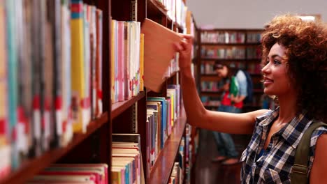 Pretty-student-retiro-de-un-libro-en-la-biblioteca