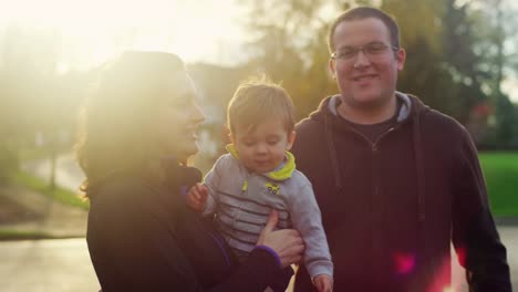 Family-of-three-posing-for-a-photo-with-lens-flare,-little-boy-trying-to-get-away