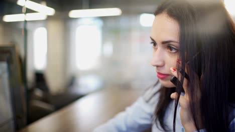 Brünette-Frau-im-Büro-während-der-Pause-drinnen-am-Telefon-sprechen