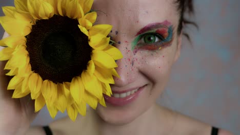 4k-schoss-einer-Frau-mit-bunten-Make-up-mit-Sonnenblume-(Schwerpunkt:-Blume)