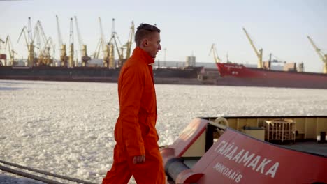 Dock-Arbeiter-in-orange-Uniform-zu-Fuß-in-den-Hafen-und-controlling-Arbeitsprozess-im-Hafen.-Vereisten-See