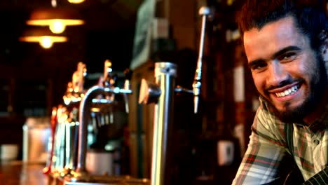 Portrait-of-smiling-barman-leaning-at-bar-counter