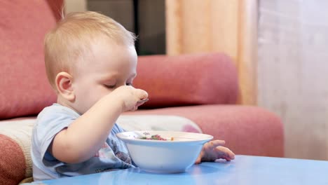 Eine-attraktive-junge-2-Jahre-alt-ist,-rote-Suppe-selbst-essen.-Löffel-und-Händen-fließt-Flüssigkeit.-Das-Konzept-einer-gesunden-Ernährung-von-Kindern