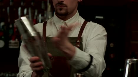 Young-handsome-barman-in-bar-interior-shaking-and-mixing-alcohol-cocktail