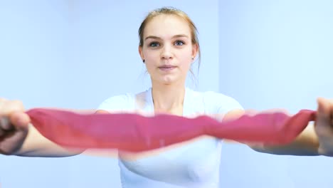 La-chica-tirando-de-la-venda-de-goma-en-la-clínica-de-rehabilitación