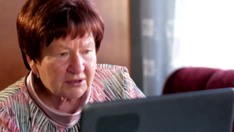 An-older-woman-checks-the-messages-on-social-networks-on-a-laptop-at-home.-She-sits-at-the-table