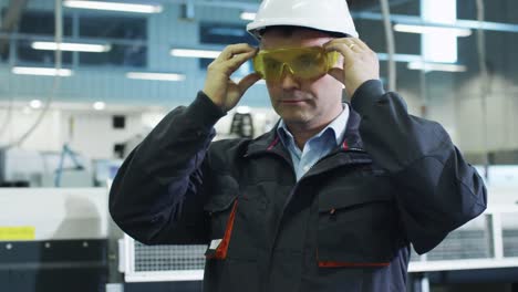 Factory-Worker-está-poniendo-sombreros-duros-y-gafas-de-seguridad