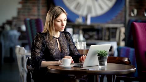 Hermosa-chica-con-laptop.-Joven-atractivo-femenino-sentada-en-café-y-uso-de-ordenador-portátil