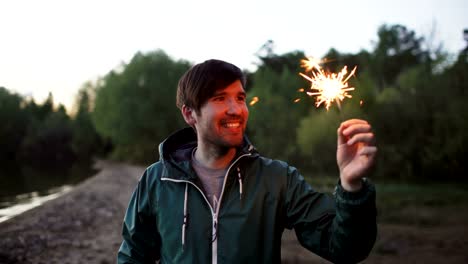 Porträt-der-jungen-lächelnd-Mann-mit-Wunderkerze-am-Beach-Party-feiern