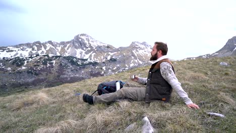 Hiker-sits-and-drinks-hot-tea-from-a-thermos