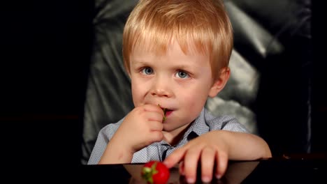 Niño-comiendo-fresas-en-fondo-negro
