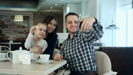 Schöne-junge-Familien-nehmen-Selfie-auf-Smartfone-und-genießen-Sie-ihre-Zeit-im-café