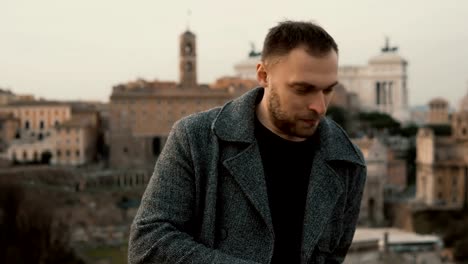 Young-handsome-man-standing-at-the-city-centre-and-looking-around.-Serious-male-waiting-for-somebody-and-sightseeing