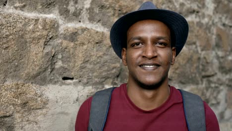 Portriat-of-happy-african-tourist-man-backpacker-smiling-and-looking-into-camera.-Mixed-race-young-guy-travelling-in-Europe