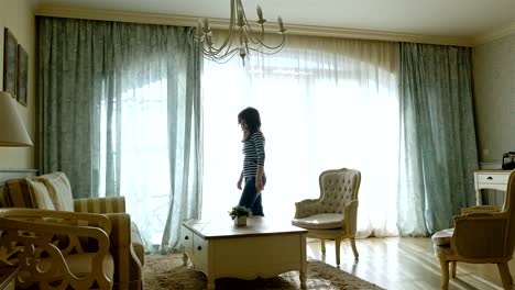 Upset-woman-going-forth-and-back-along-the-window-of-a-cozy-apartment