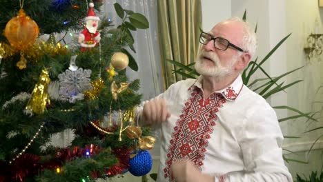 Old-attractive-grandfather-decorates-a-Christmas-tree-at-home