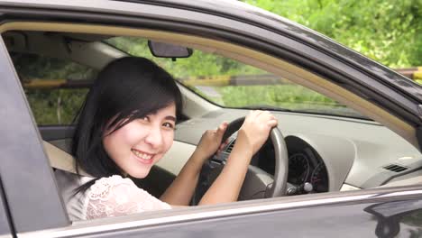 Asian-Portrait-of-young-smiling-woman-sitting-in-the-car