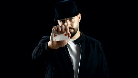 Professional-Street-Magician-in-a-Cap-Performs-Impressive-Sleigth-of-Hand-Card-Trick.-Background-is-Black.